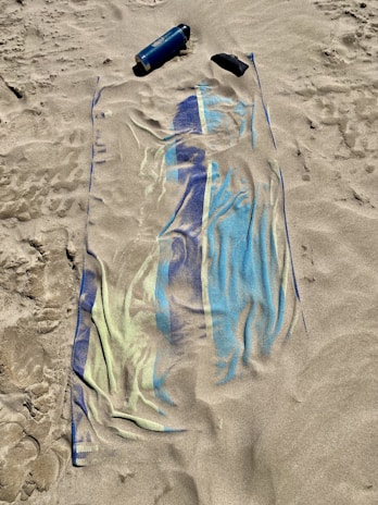 A sunlit scene featuring sunscreen bottles on a beach towel.