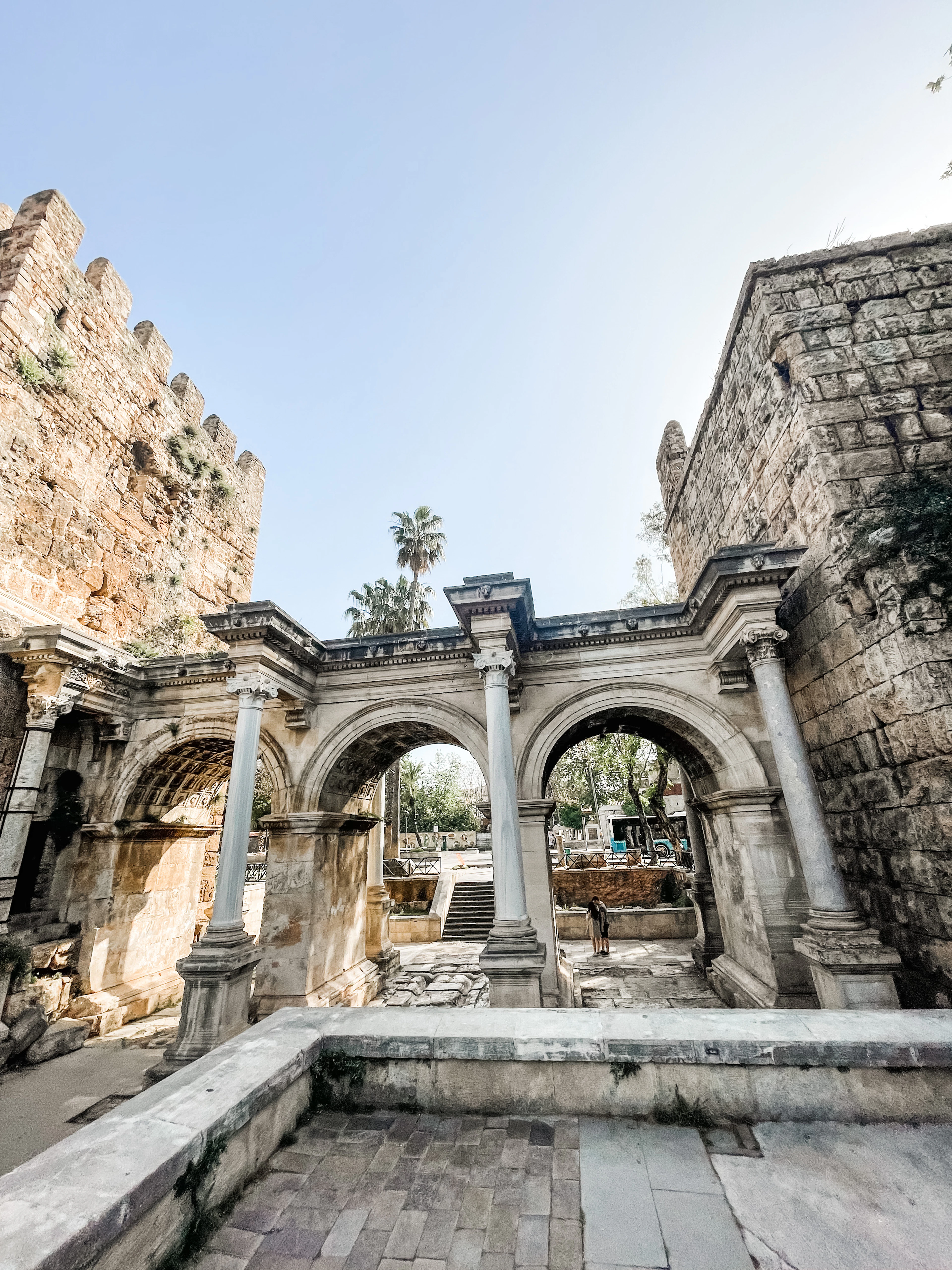 Hadrian's Gate in Antalya's Kaleici — three marble arches on Corinthian columns set between the old town's stone walls