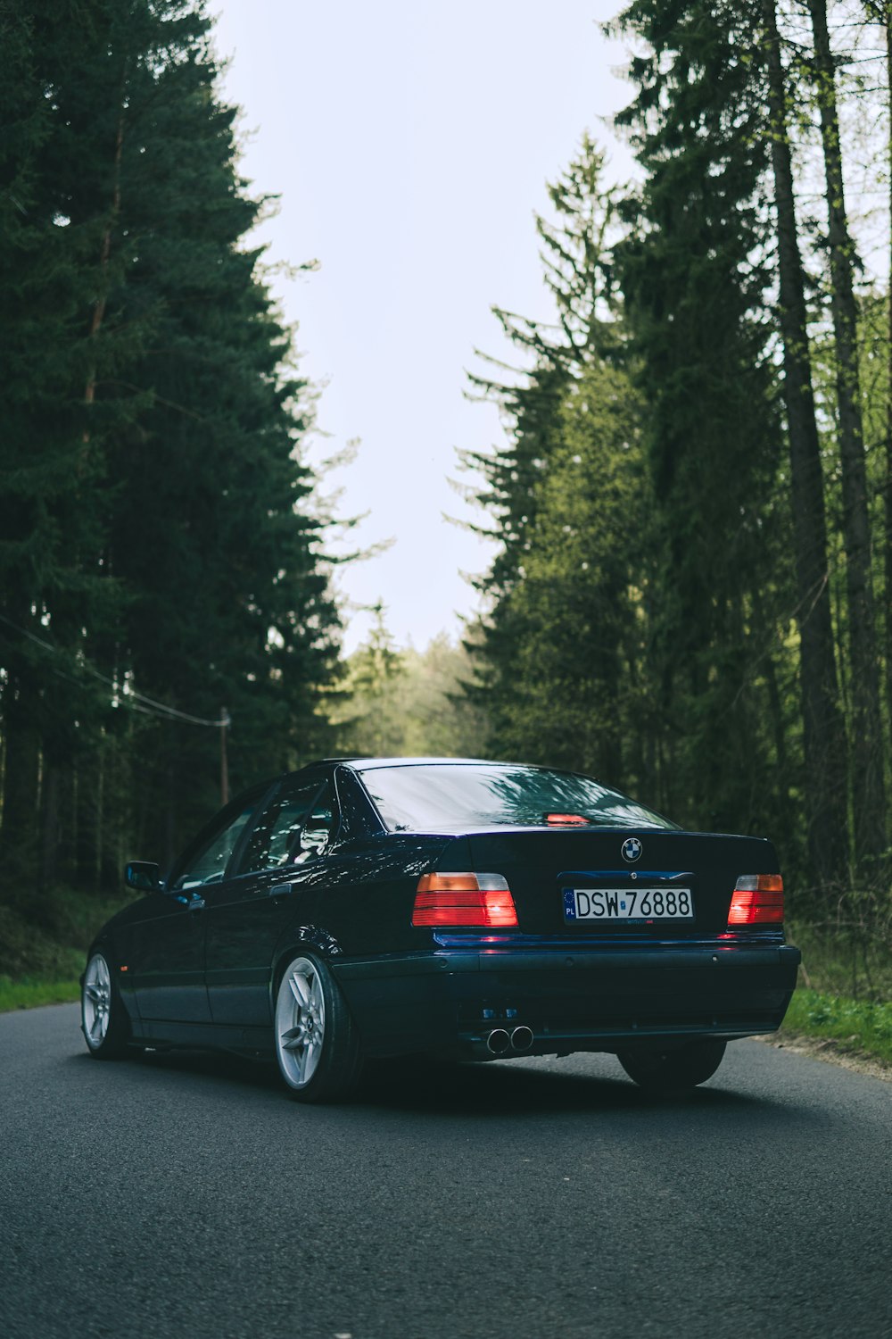 a black car parked on a road with trees on either side