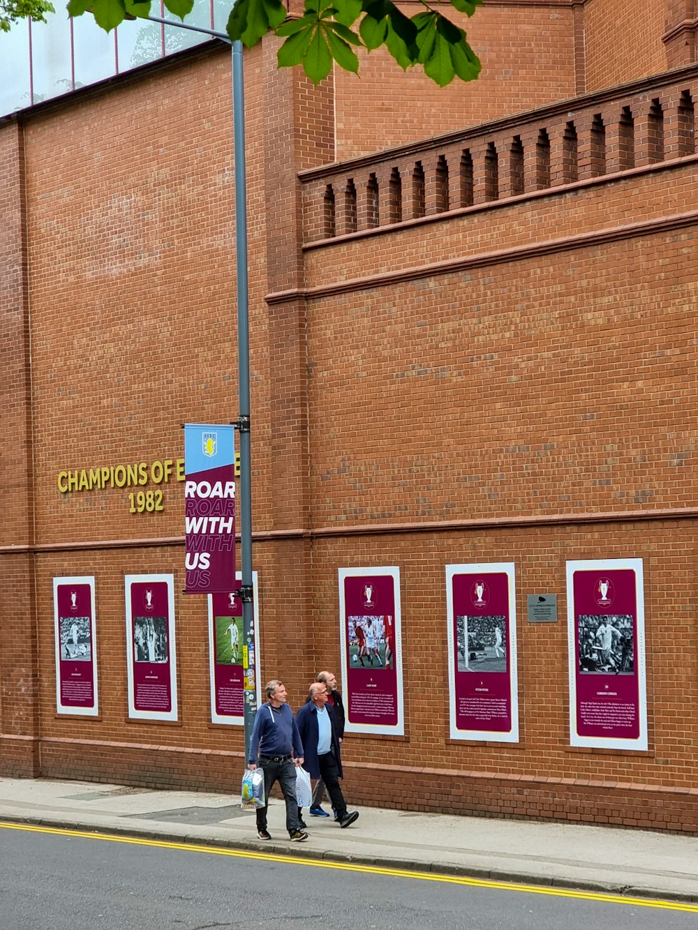 a couple of people standing in front of a brick building with posters on it