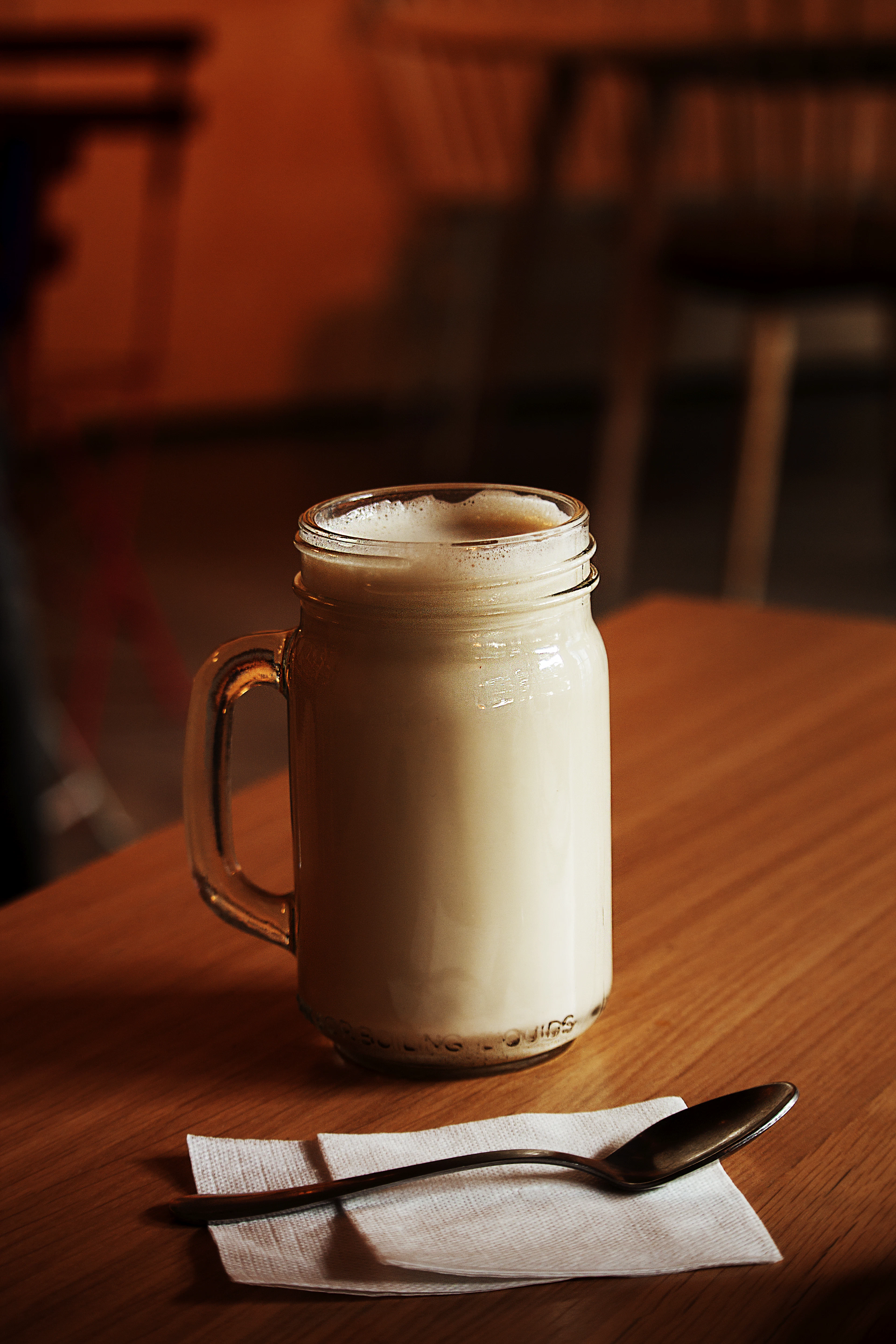 Chai latte in a glass mug on a red table