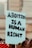 A sign being held at a protest that reads 'Abortion is a Human Right' in bold, black letters on a light blue background. The sign is in focus, while the background appears to be a blurred crowd and a building.