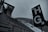 A large stairway in an outdoor stadium setting with overcast skies, alongside signage with letters H and G in bold. The bleachers are empty and there is a structure with Olympic rings attached, hinting at a sports venue.