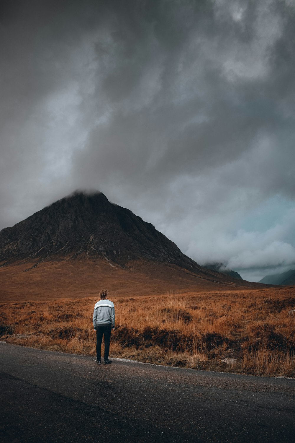 a person standing on a road with a mountain in the background