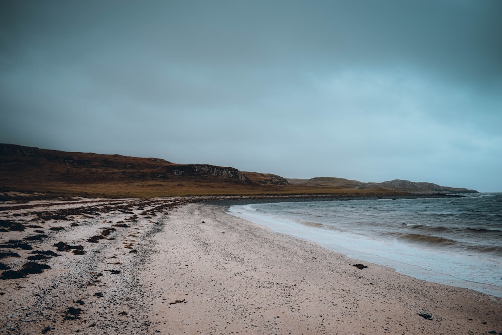 a sandy beach with hills in the background