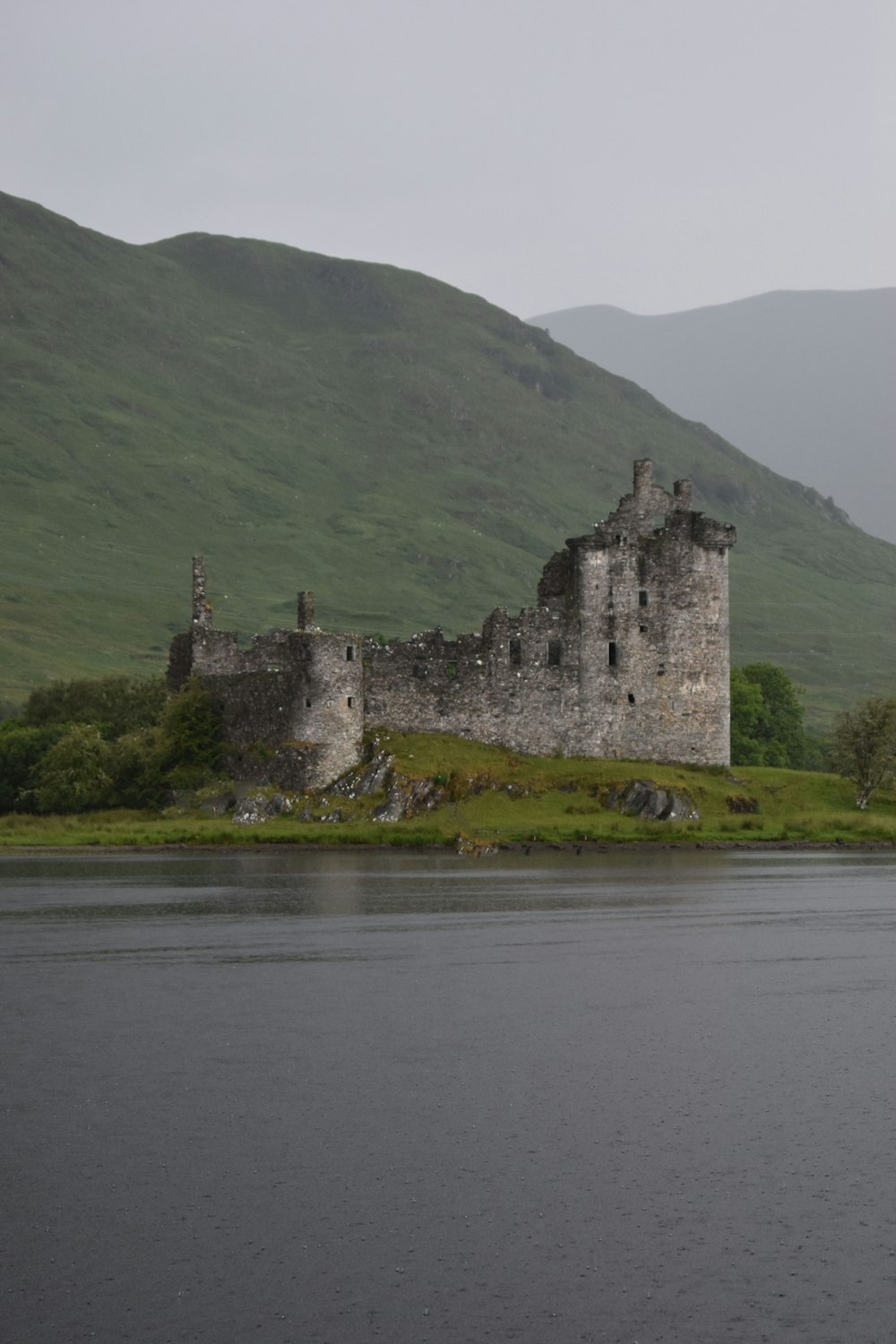 a castle on a hill by a lake