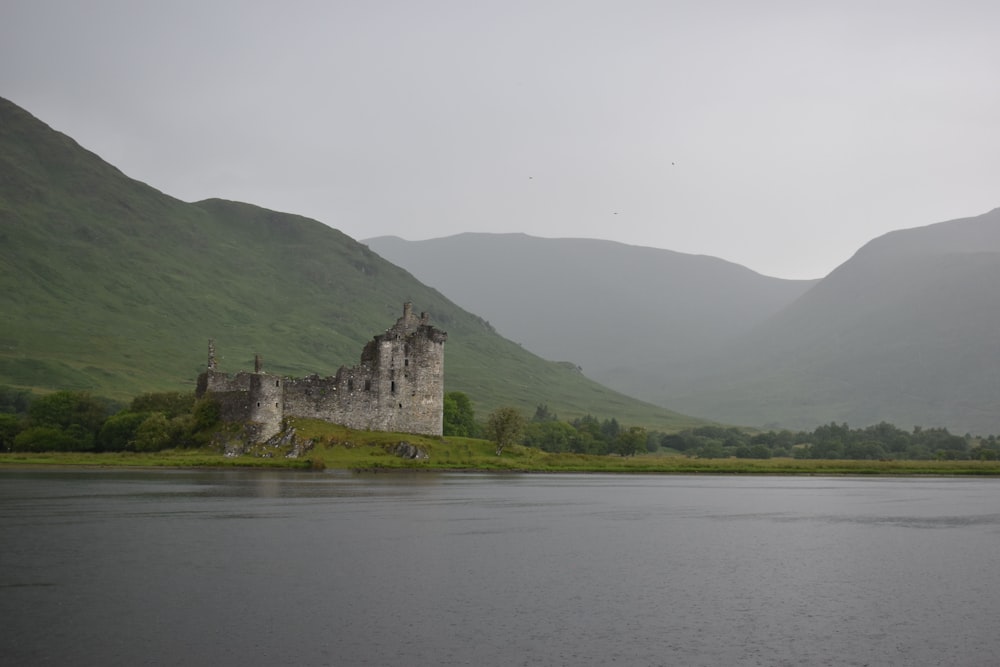 a stone castle on a hill by a lake