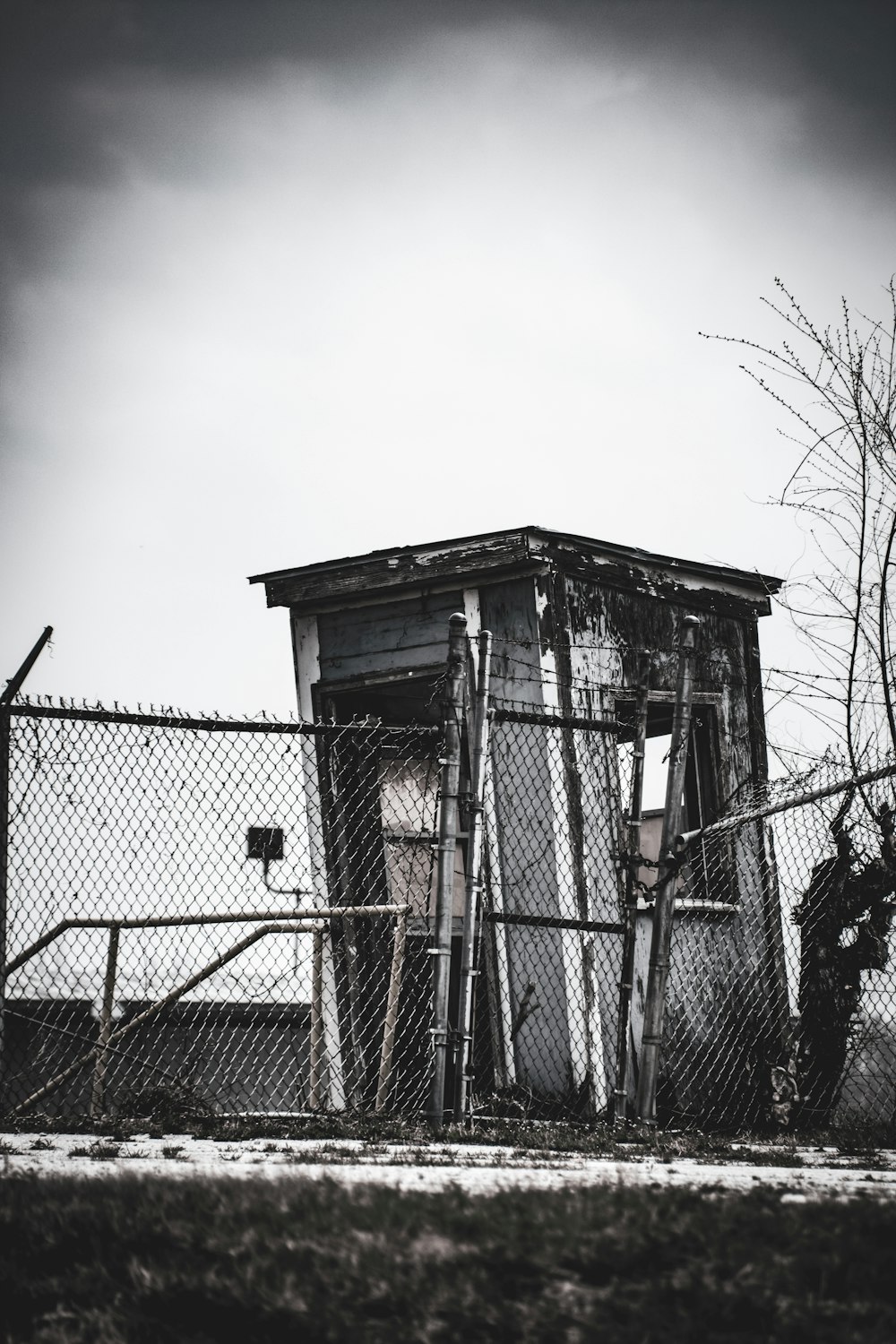 a fenced in building with a gate and trees in the background