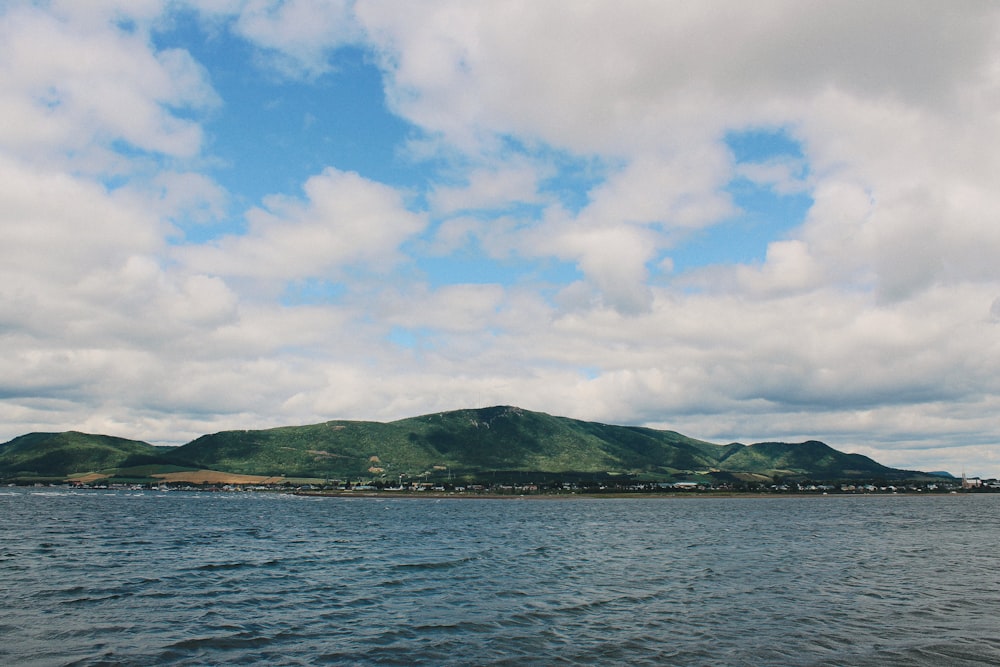 a body of water with a hill in the background