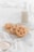 A few sugar-coated pastries with a lattice shape are placed on a metal cooling rack. The background features a glass bottle filled with milk. A white cloth and a small bowl of sugar are also visible, creating a soft, inviting baking scene.