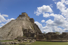 a stone pyramid with grass and blue sky