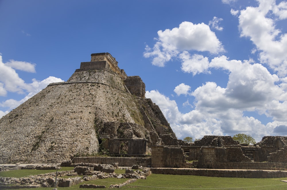 a stone pyramid with grass and blue sky