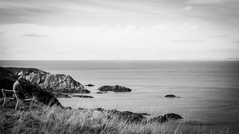 a person sitting on a chair on a cliff overlooking the ocean