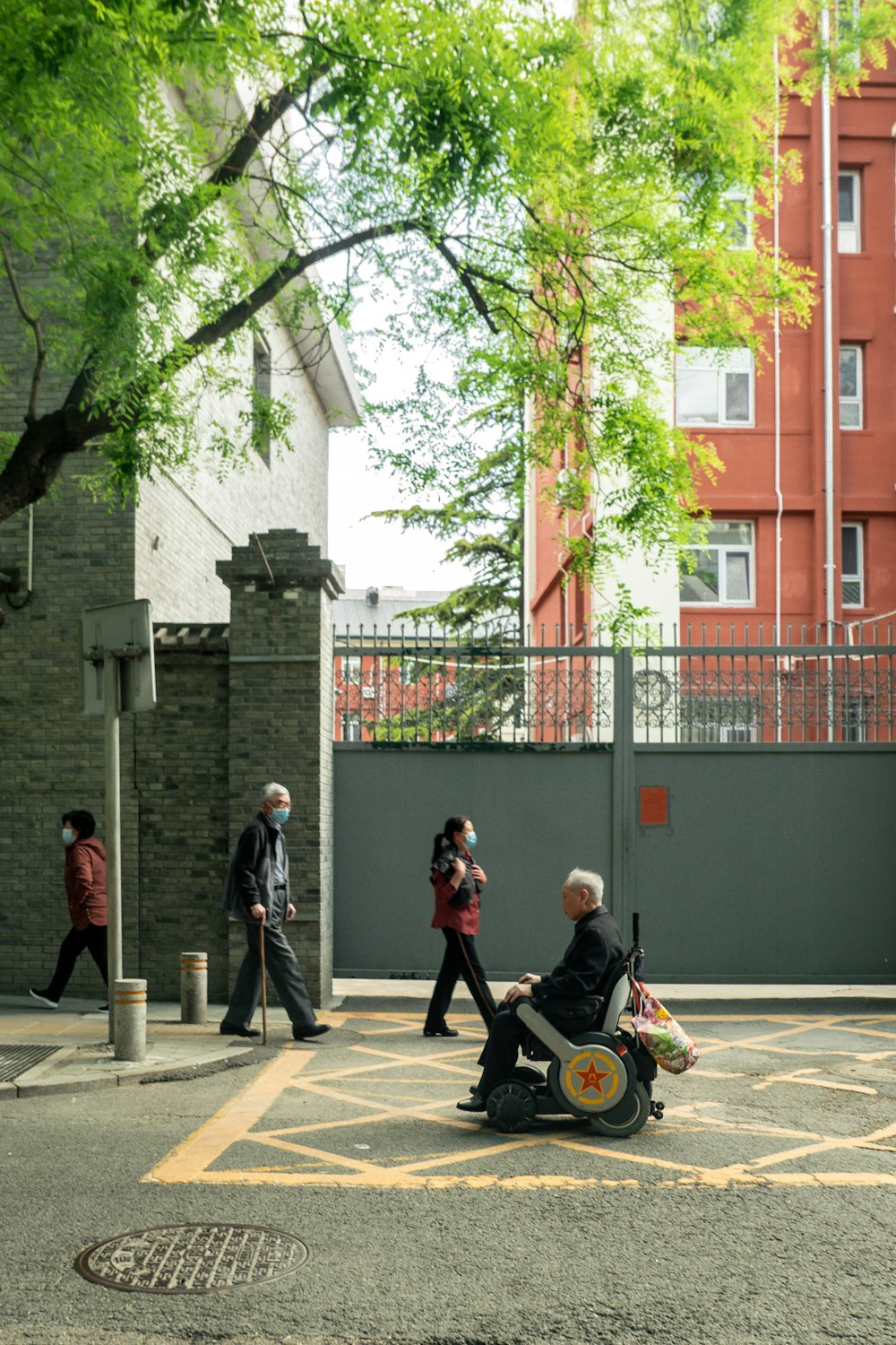 a person in a wheelchair on a street with people walking by