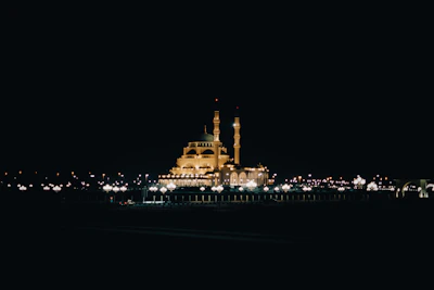 A serene shot of Masjid al-Haram's illuminated minarets against the night sky.