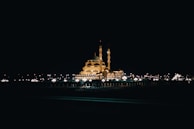 Night view of the illuminated Masjid al-Nabawi, glowing under a starry sky.