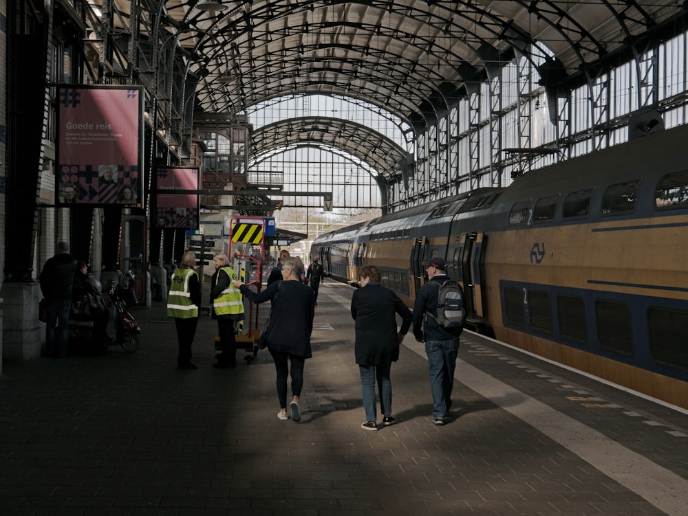 電車の横のプラットホームを歩く人々