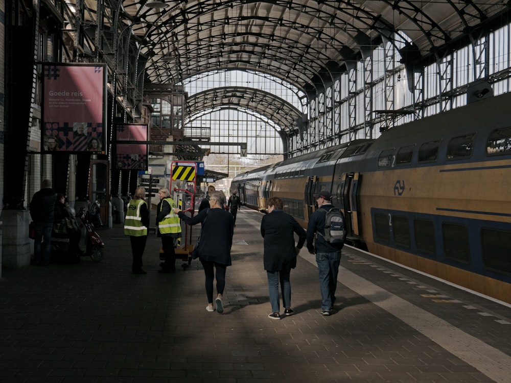 people walking on a platform next to a train