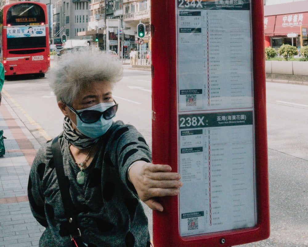 a person wearing a mask and a scarf standing next to a sign