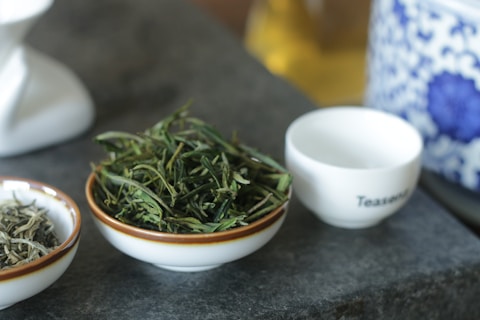 Tea leaves placed on a plate, with a teacup beside it