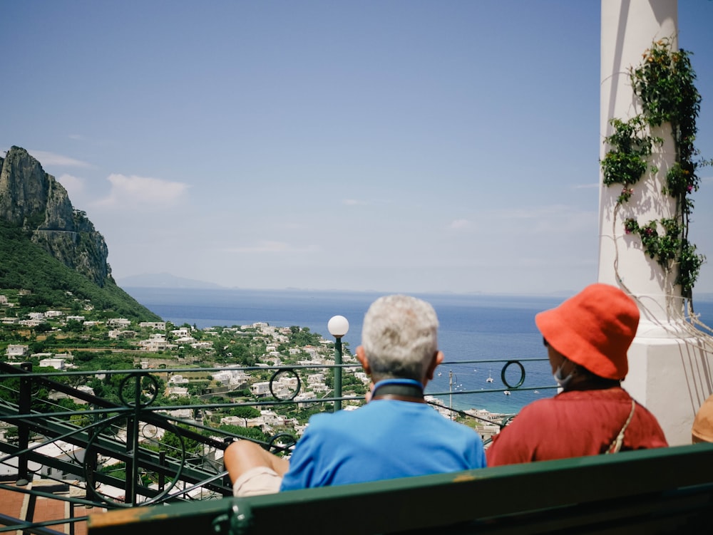 um casal sentado em uma varanda com vista para uma cidade e para o oceano