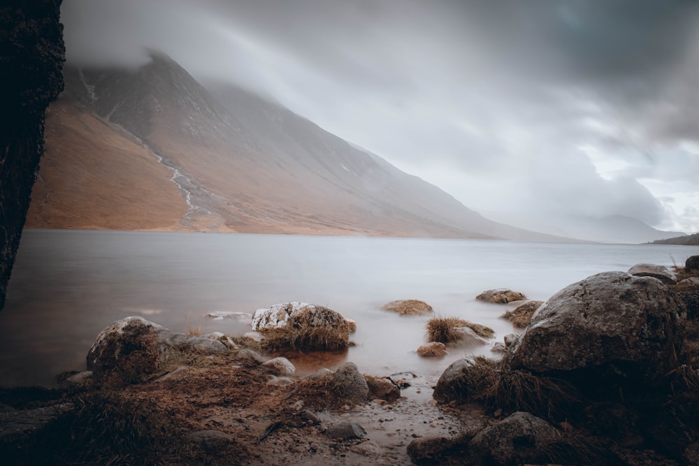 a rocky beach with a large body of water in the background