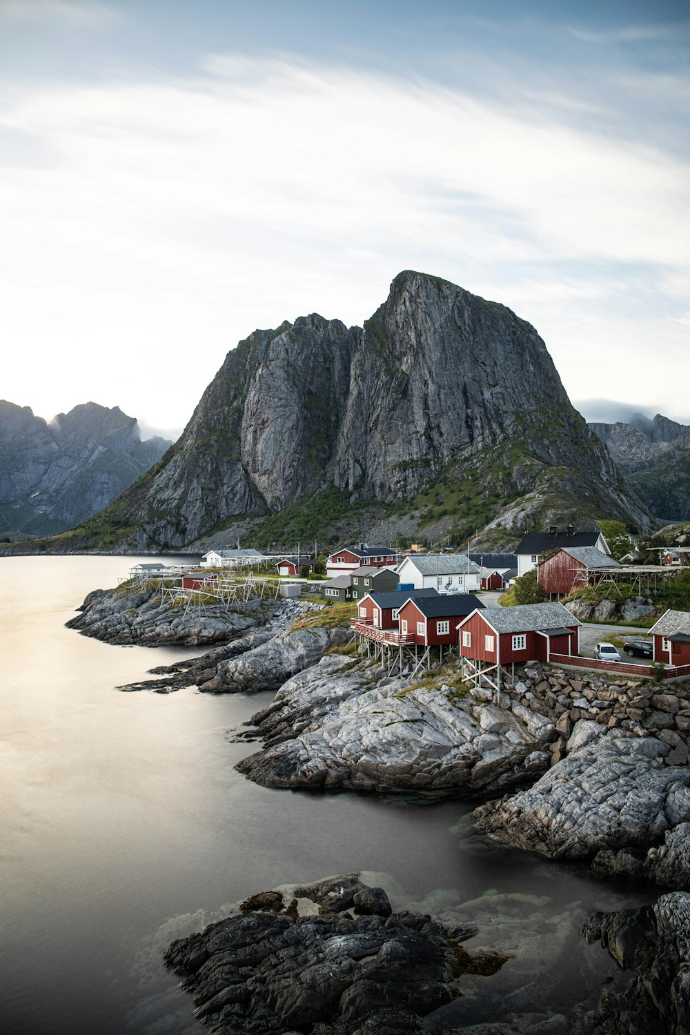 a group of houses by a body of water with Lofoten in the background
