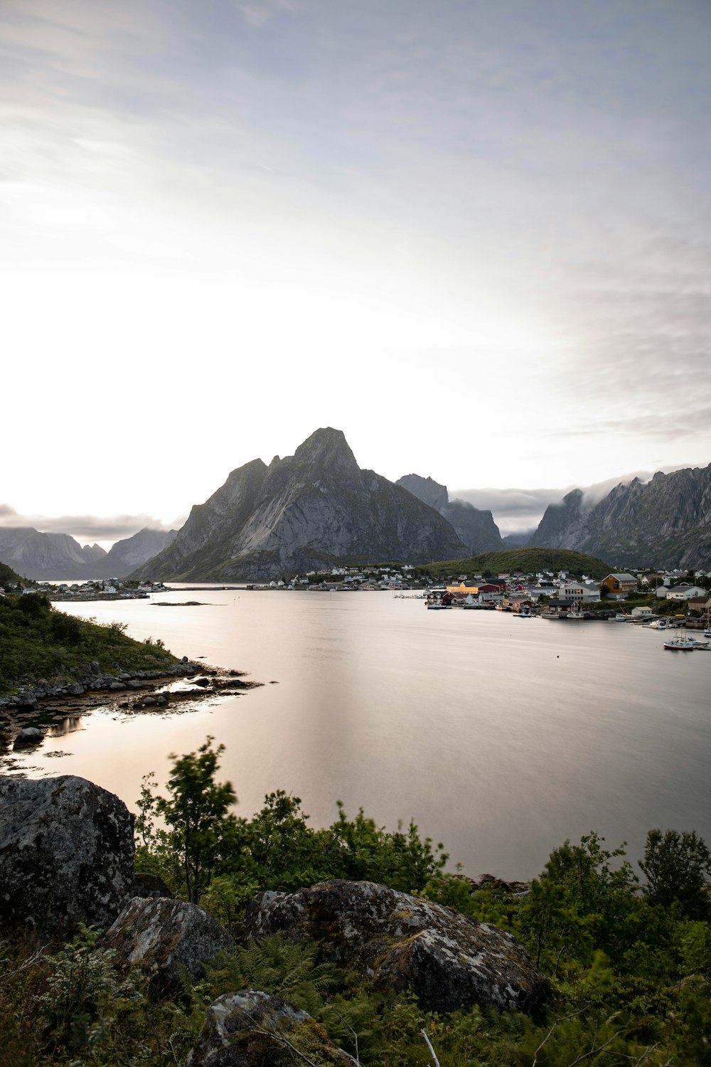 a body of water with a town by it and mountains in the background