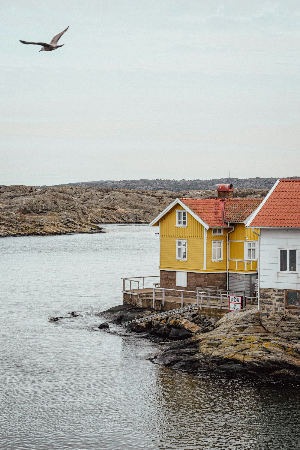 a yellow house on a rocky shore