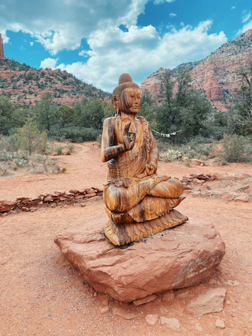 A close-up of a handcrafted medallion resting on red Sedona rocks with a scenic vortex site in the background.