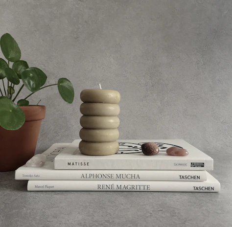An artfully arranged stack of vintage books topped with a tiny surreal sculpture.
