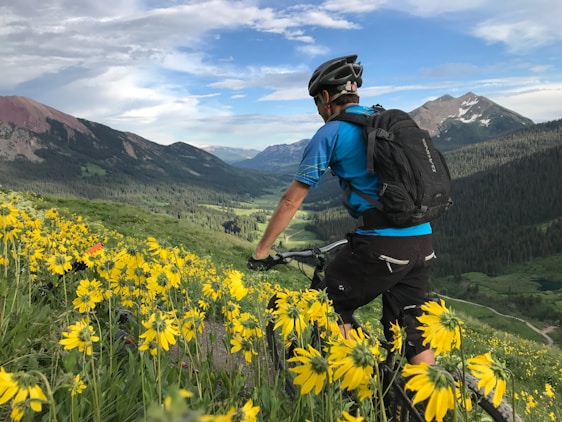 A cyclist adjusting their helmet with a scenic mountain trail in the background.