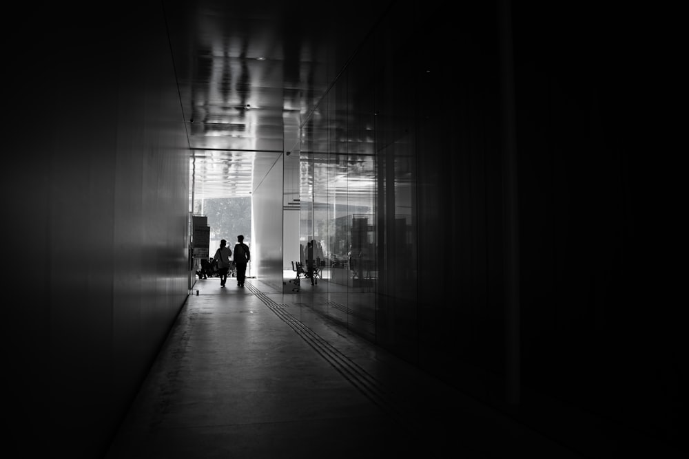 a black and white photo of people walking in a hallway