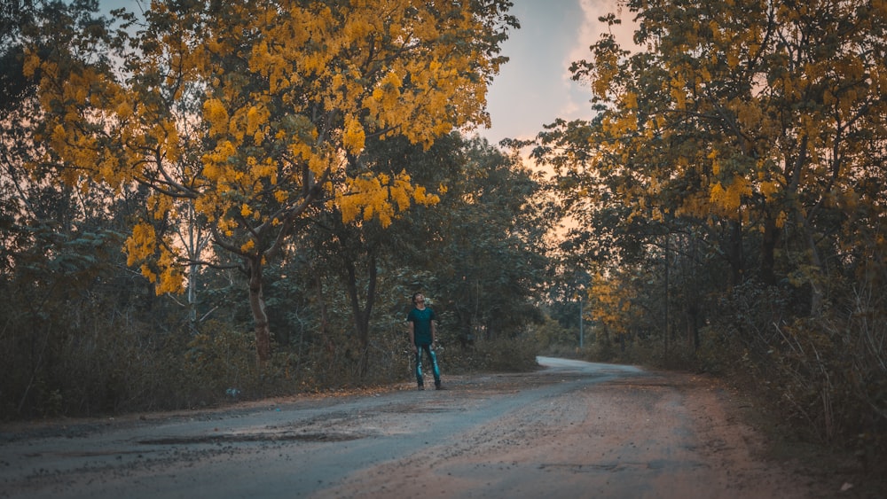 a person standing on a road surrounded by trees