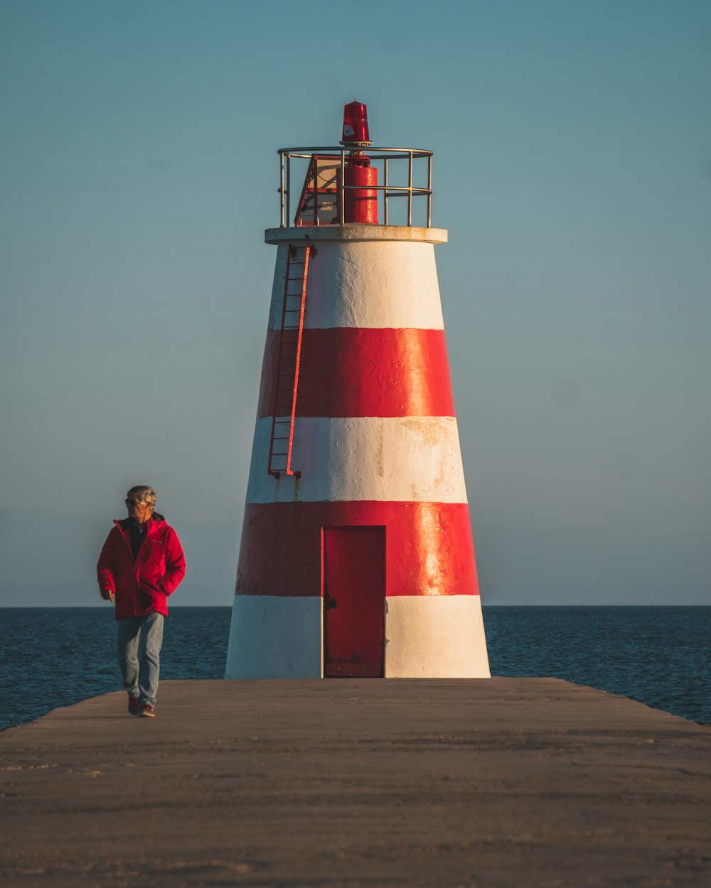 a person standing next to a red and white lighthouse