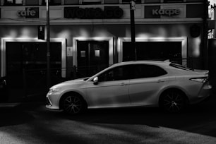 Front view of a sleek white Toyota sedan parked on a city street.