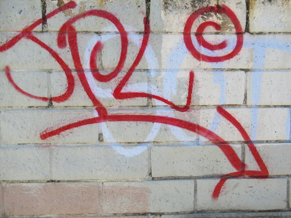 Un graffito rosso e bianco su un muro bianco