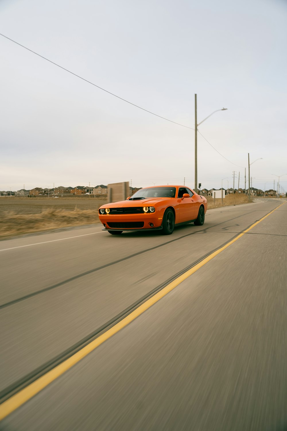 um carro esportivo laranja dirigindo em uma estrada