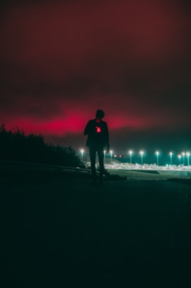 a person standing on a road with a fire in the background