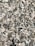 A close-up view of a granite surface with a coarse, speckled pattern. The stone features a mix of black, white, and gray crystals with some pinkish areas, giving it a textured and natural appearance.