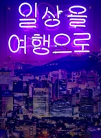 A modern cityscape at night, illuminated with neon lights from a Kdrama.