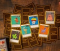 A collection of trading cards is laid out on a wooden surface. The cards feature cartoonish illustrations of various creatures with humorous names like 'A Bird With Slides,' 'The Party Mushroom,' and 'Izita Cat.' The brown backing of several cards shows the logo 'Toons and Towers.' Each card includes stats like 'Attack' and 'Defense' and a playful description.