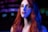 A woman with long, wavy red hair is photographed against a blurred background featuring bokeh lights. Her face is illuminated with a blue light on one side, creating a striking contrast with her hair and skin tone. Her expression is neutral, with slightly parted lips and intense eyes.