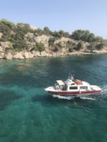 A small boat cutting through turquoise waters beneath a clear sky, with passengers enjoying the sea breeze.