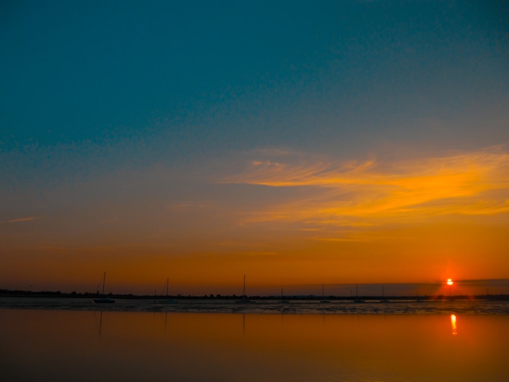 a body of water with boats in it and a sunset in the background