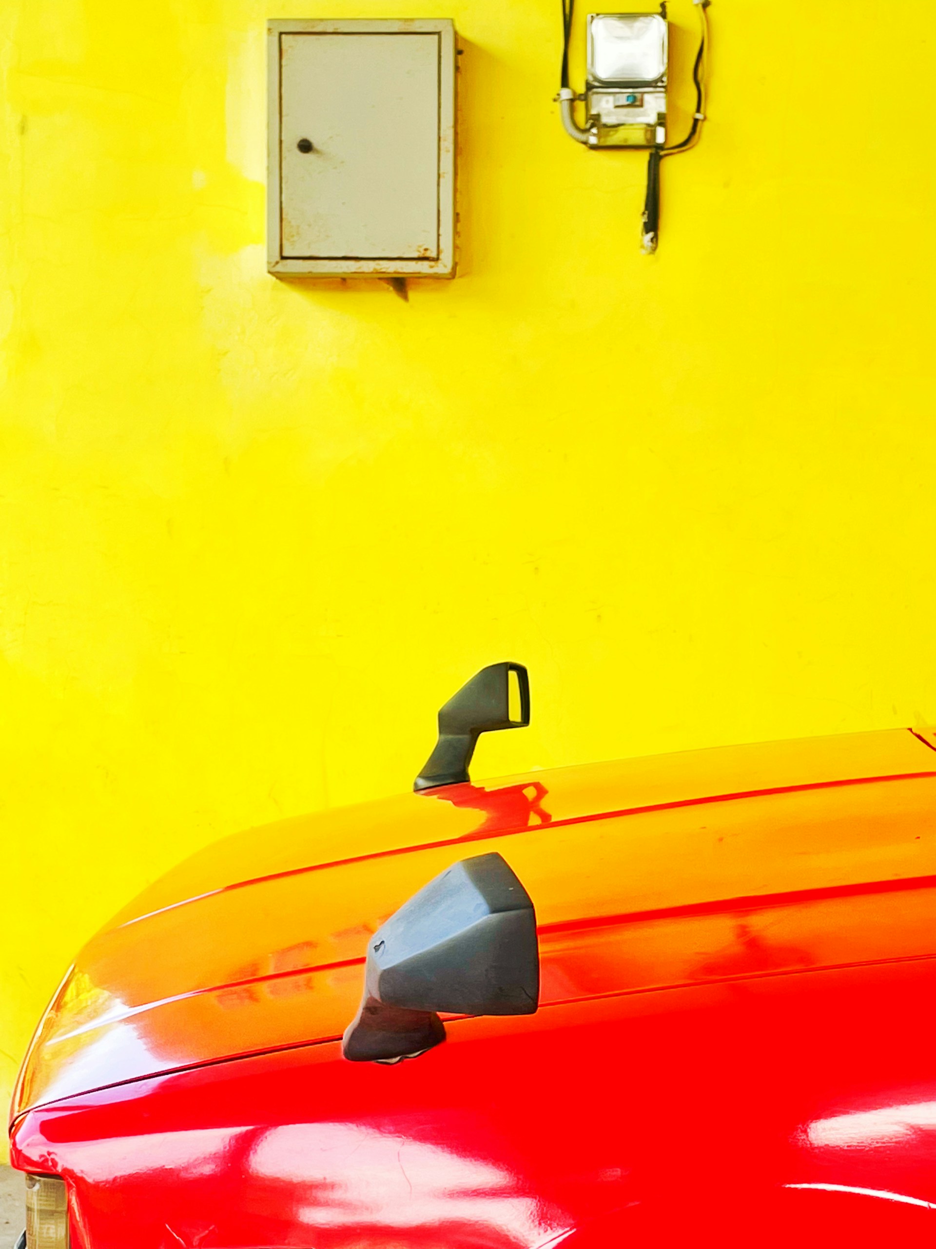 a red car with a yellow wall behind it