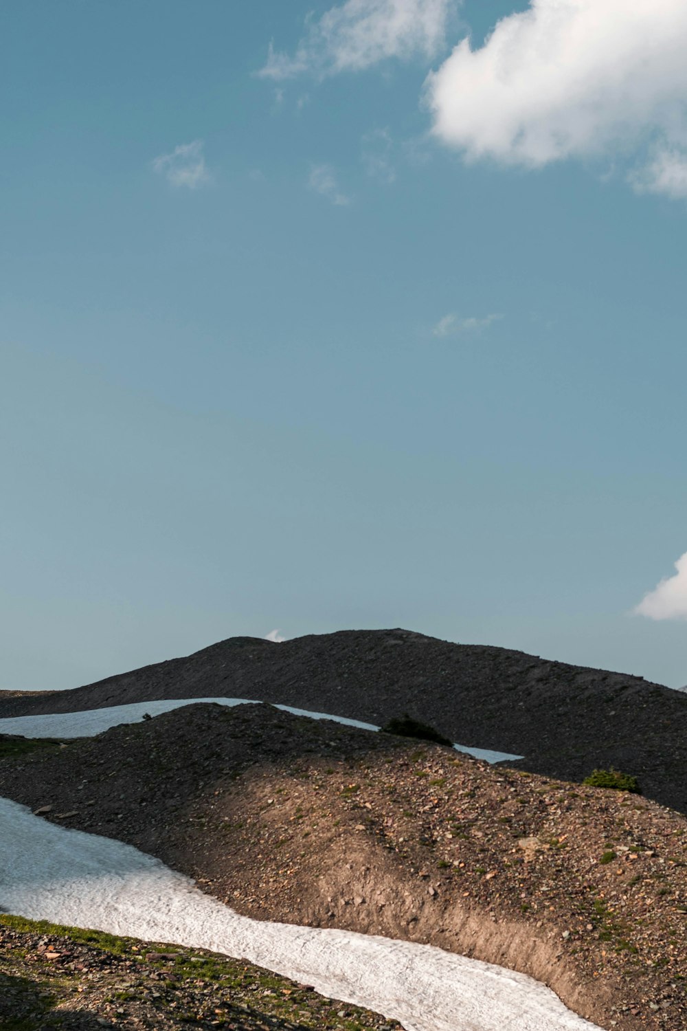 a landscape with a body of water and a hill with a blue sky