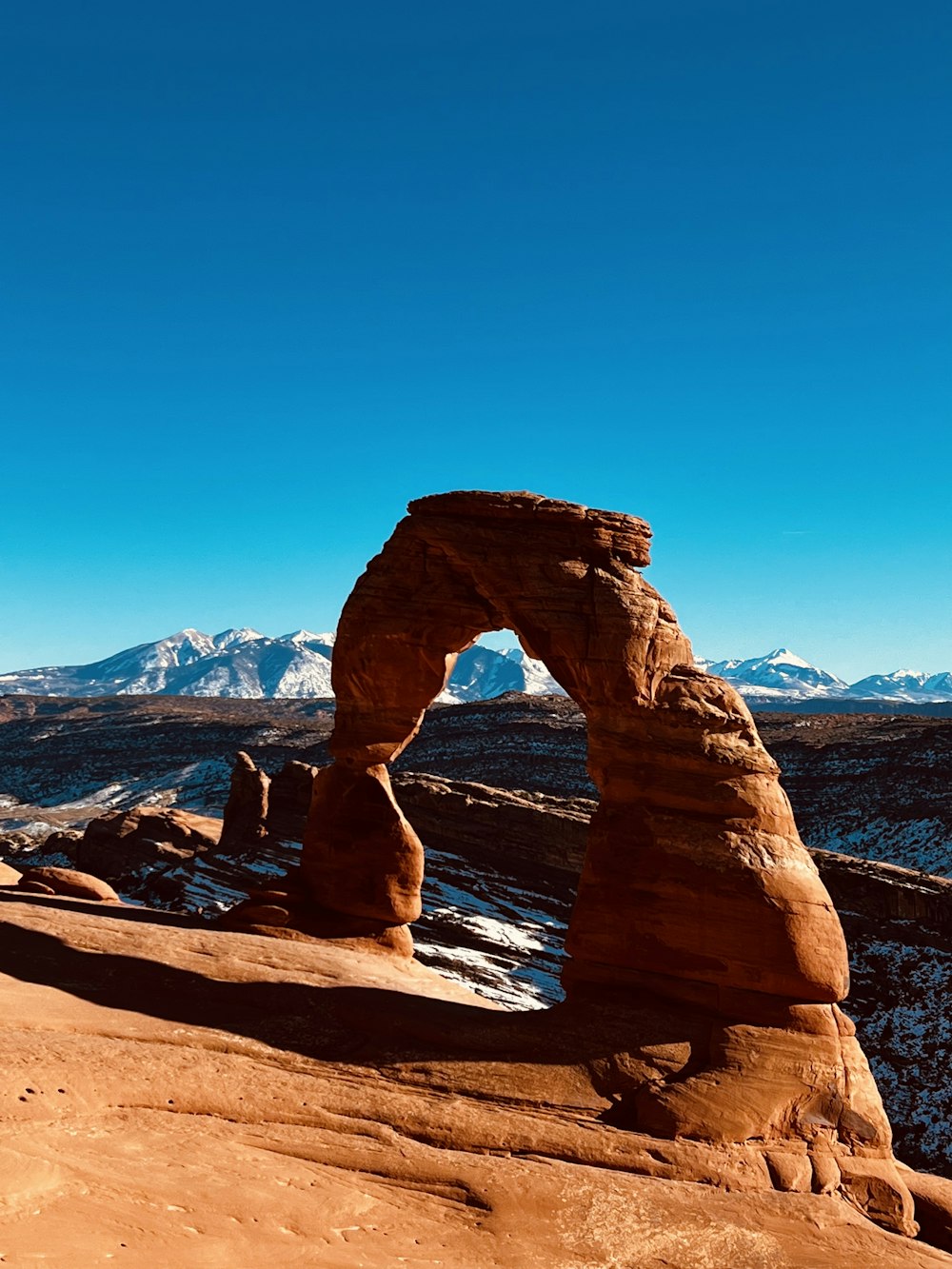 a large rock formation in the desert with Arches National Park in the background