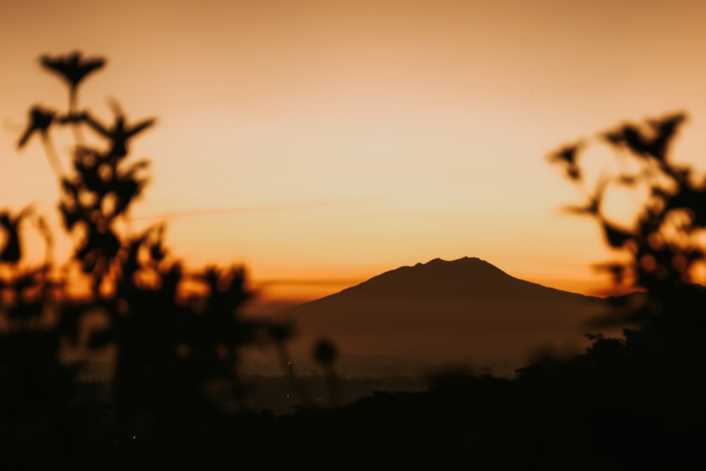 una silueta de una montaña y una puesta de sol