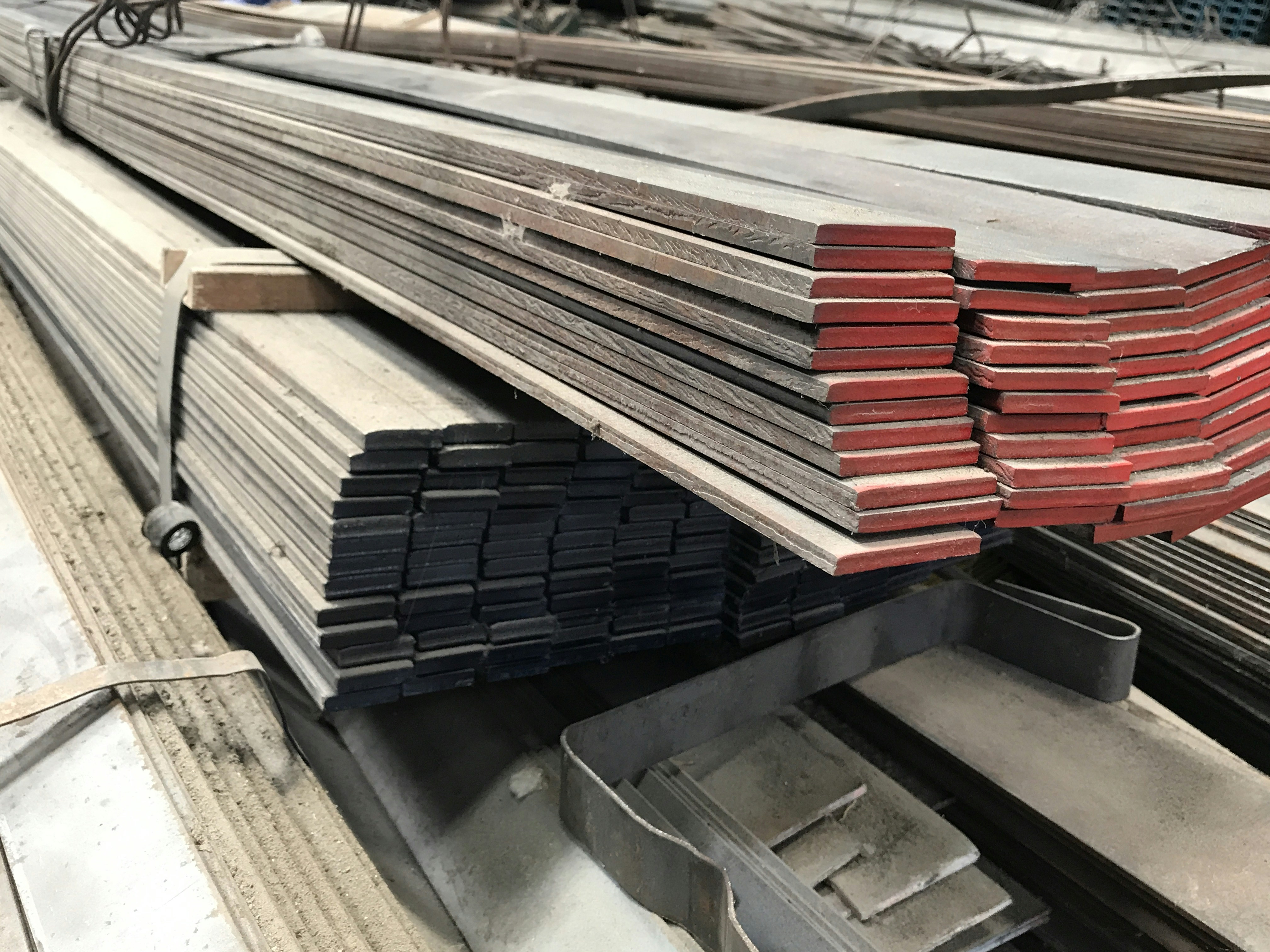 Hexagonal bright steel bars bundled in warehouse, six-sided metallic profile, industrial dark background